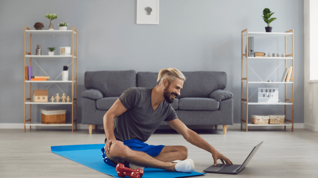 A person doing yoga on a mat in front of a laptop