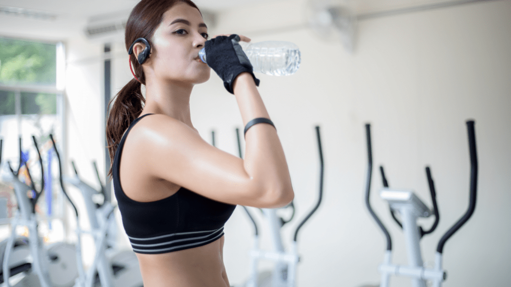 A person is drinking water from a bottle in a gym