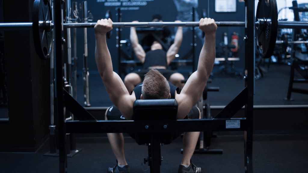 A person is laying on a bench in a gym