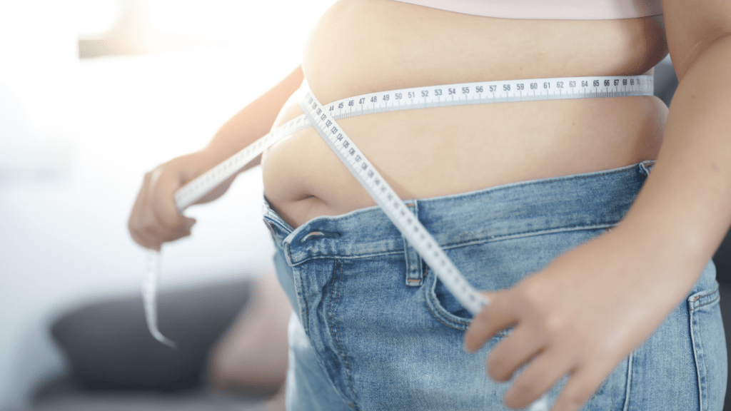 A person measuring their waist with a tape measure