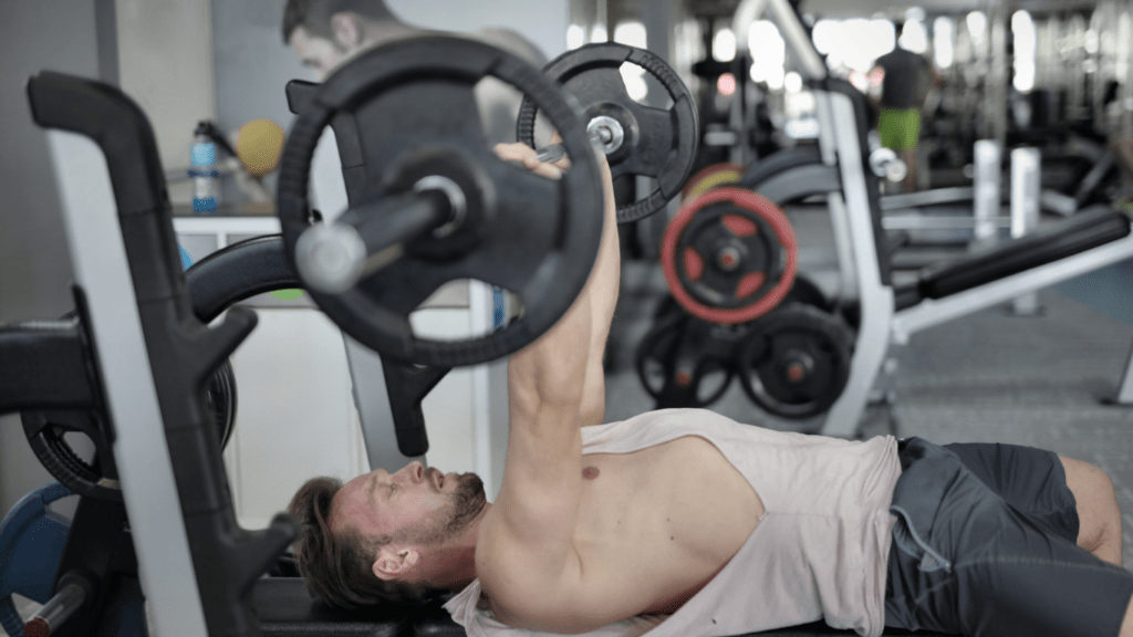 A person is laying on a bench in a gym