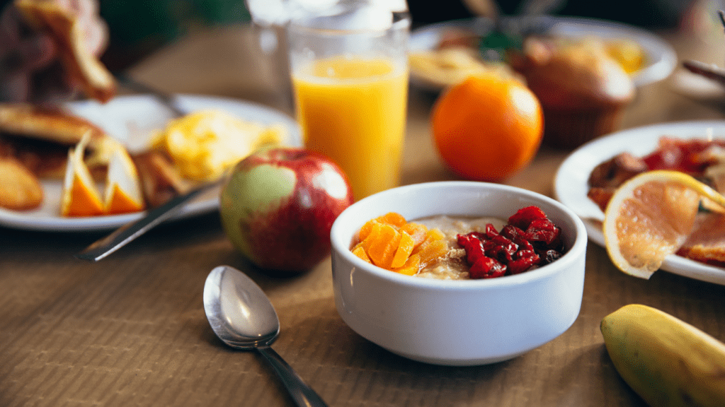 a bowl of oatmeal, fruit and orange juice on a table