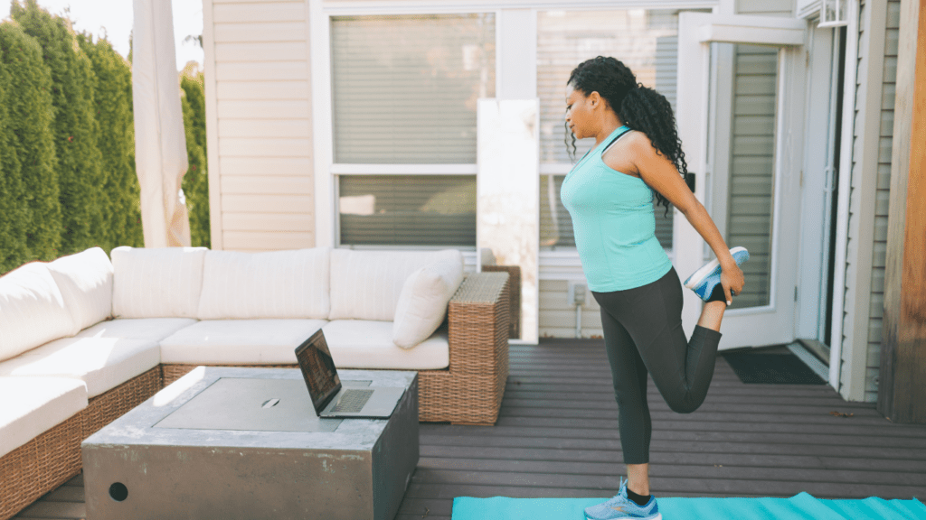 A person doing yoga on a mat in front of a laptop