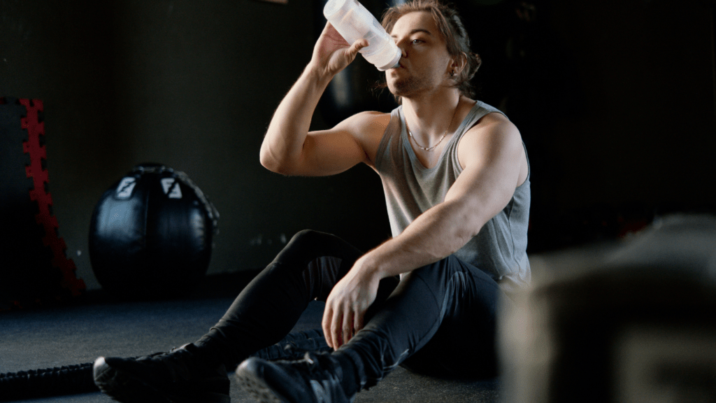 A person is drinking water from a bottle in a gym