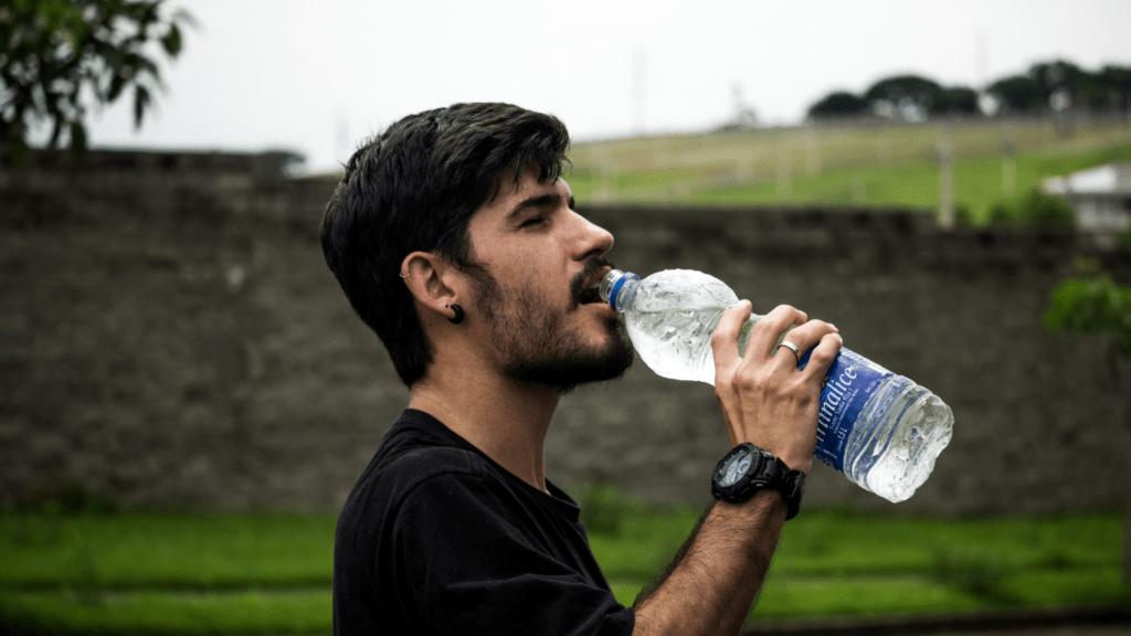 a person drinking water from a bottle on a dirt road