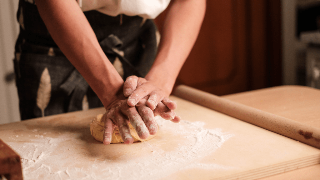 a person in an apron kneading dough in the kitchen