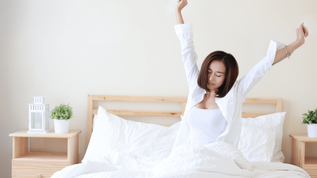 a person is laying on their bed with their arms up in the air