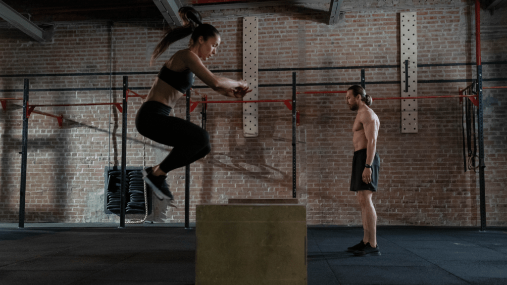 a person is standing on top of a box in a crossfit gym