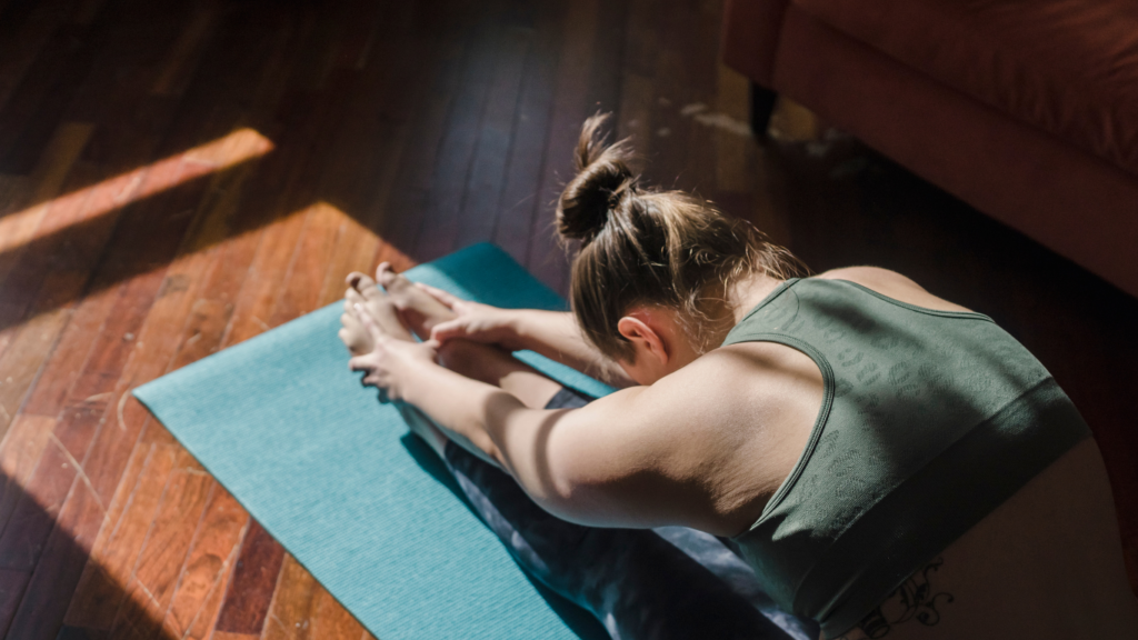 a person stretches their legs while sitting on a mat